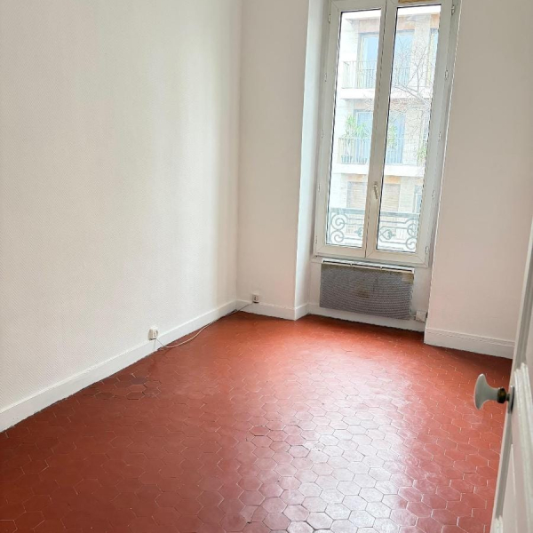 Une petite pièce avec un sol carrelé rouge et une fenêtre.