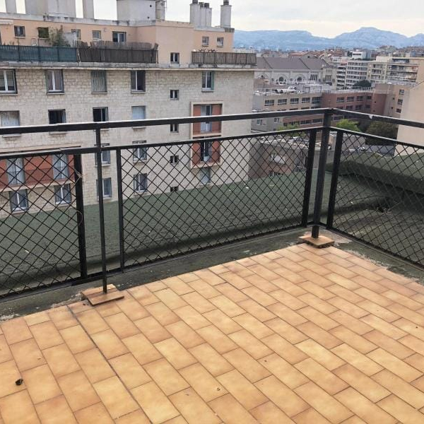Balcon avec garde-corps en treillis et vue sur les immeubles environnants.