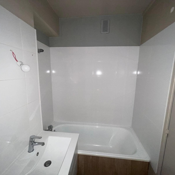Une salle de bain blanche et minimaliste avec une baignoire et un lavabo.