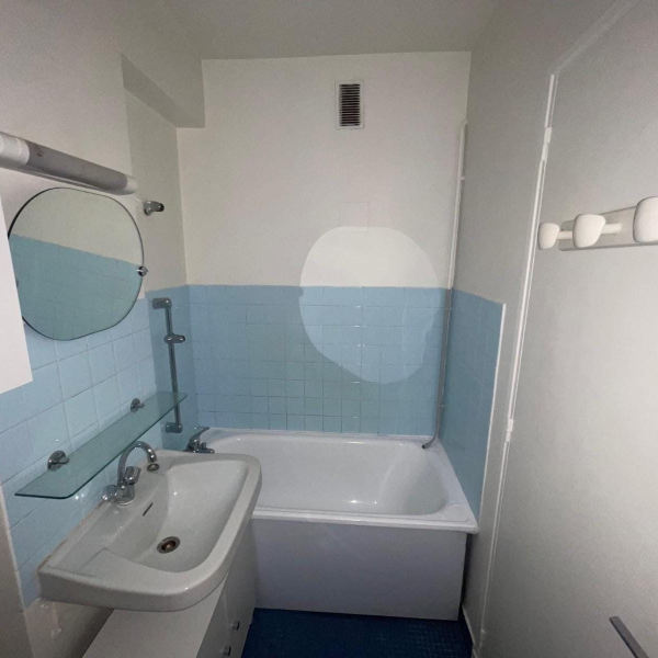Une petite salle de bain blanche avec des carreaux bleu clair et une baignoire.