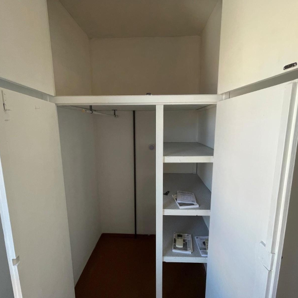 Intérieur d'une armoire blanche vide avec des étagères et une barre de penderie.