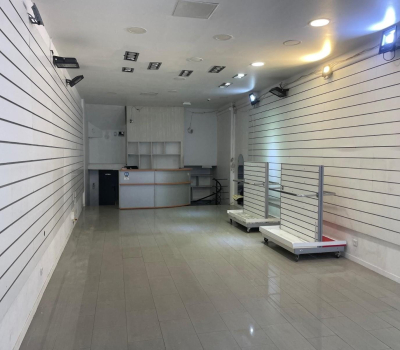 Intérieur d'une boutique vide avec des murs blancs à rainures et un comptoir au fond.
