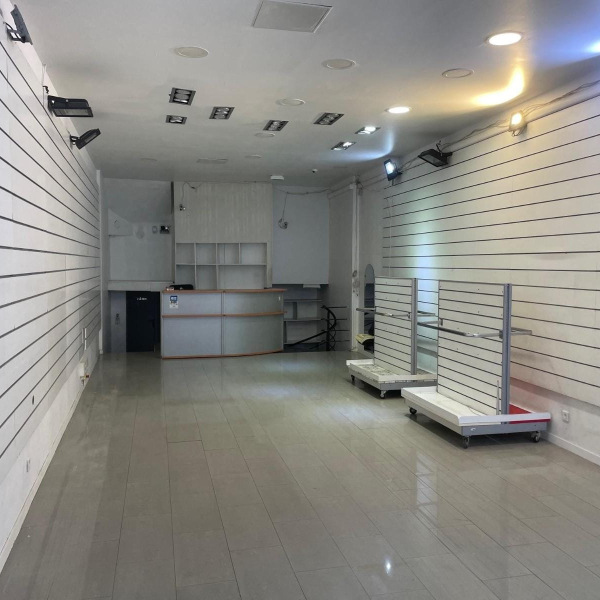 Intérieur d'une boutique vide avec des murs blancs à rainures et un comptoir au fond.