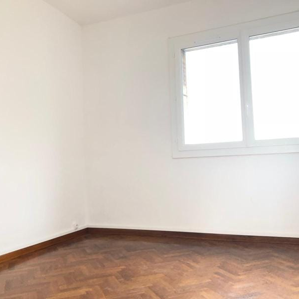 Une pièce vide avec une fenêtre et un sol en parquet.