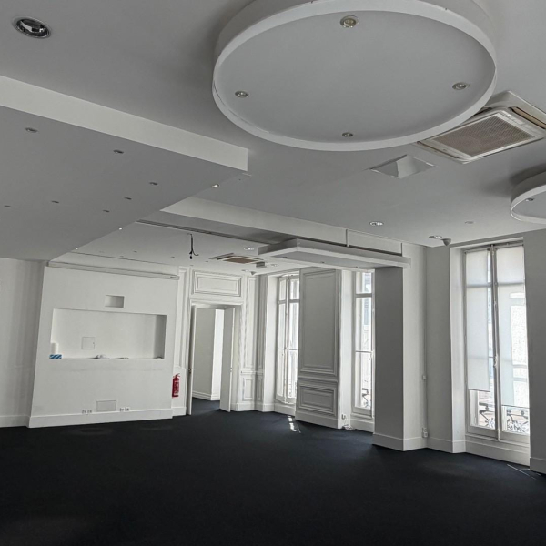 Intérieur d'une pièce vide et moderne avec des murs blancs, un sol noir et des plafonds design.