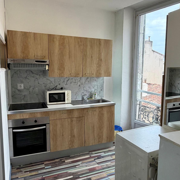 Une petite cuisine équipée avec des placards en bois clair, un four et un micro-ondes.
