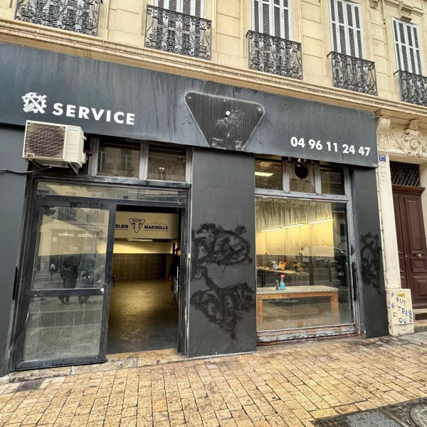 Vitrine d'un commerce à Marseille, avec l'enseigne "SERVICE" et un numéro de téléphone.