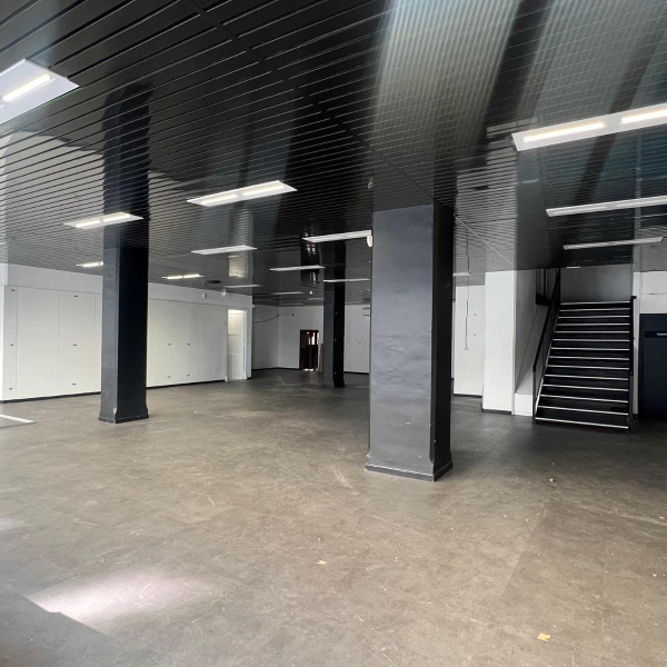 Intérieur d'un grand espace vide et moderne avec un plafond noir brillant, des piliers noirs et un escalier.
