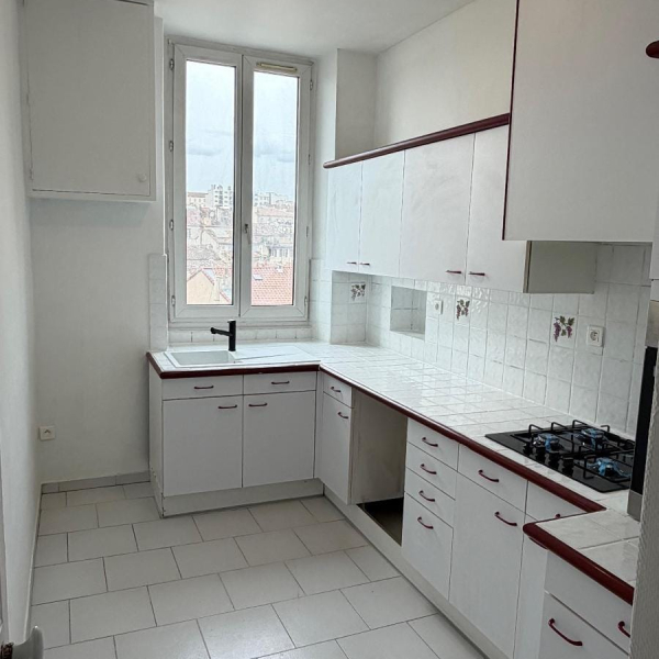 Cuisine d'un petit appartement avec évier, plaque de cuisson et armoires blanches.