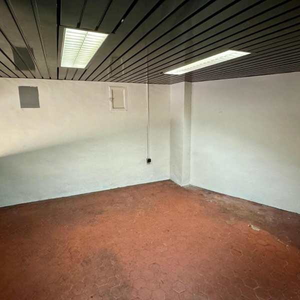 Pièce vide et neutre avec un sol en carrelage rouge et un plafond métallique.