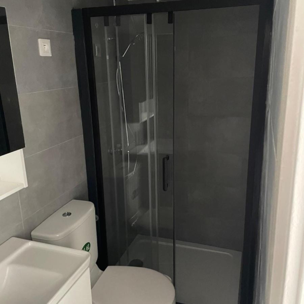 Une salle de bain moderne avec un lavabo, des toilettes et une douche avec un cadre noir.