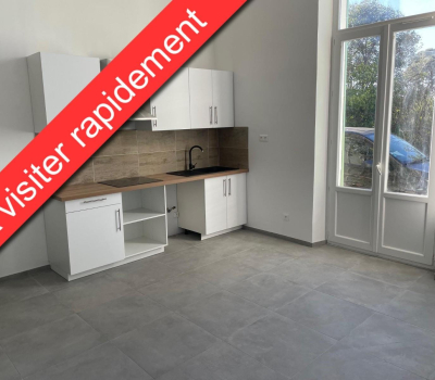 Cuisine moderne blanche avec plan de travail en bois et sol en carrelage gris, à côté d'une porte-fenêtre.