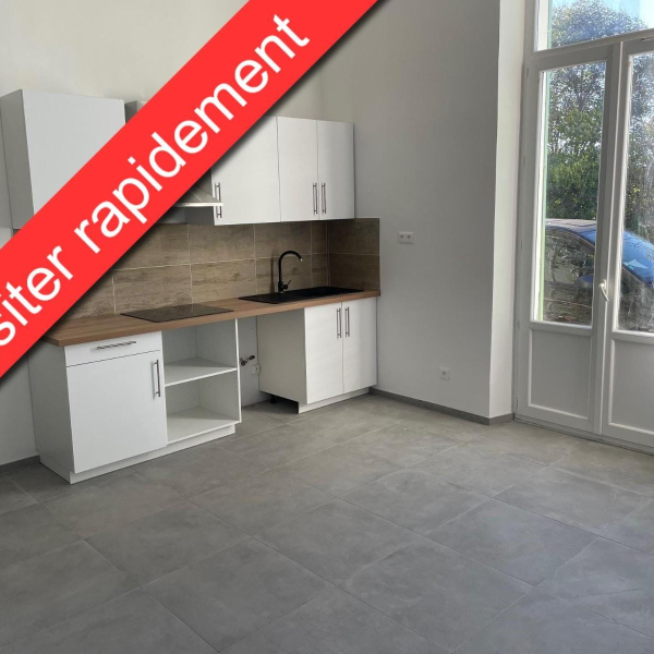 Cuisine moderne blanche avec plan de travail en bois et sol en carrelage gris, à côté d'une porte-fenêtre.